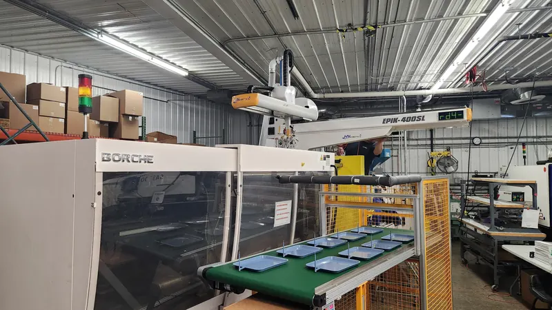 Injection moulding machine with a robotic take-out arm on a production floor