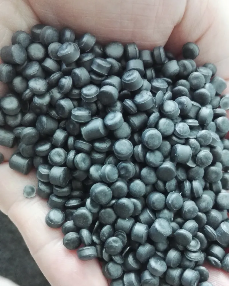 Dark polymer pellets for injection moulding held in a hand