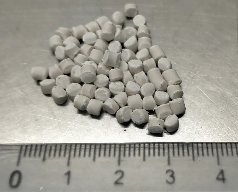 Grey compound pellets beside a millimetre ruler