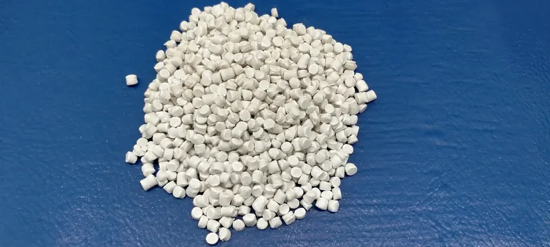 A pile of white compound pellets on a blue surface
