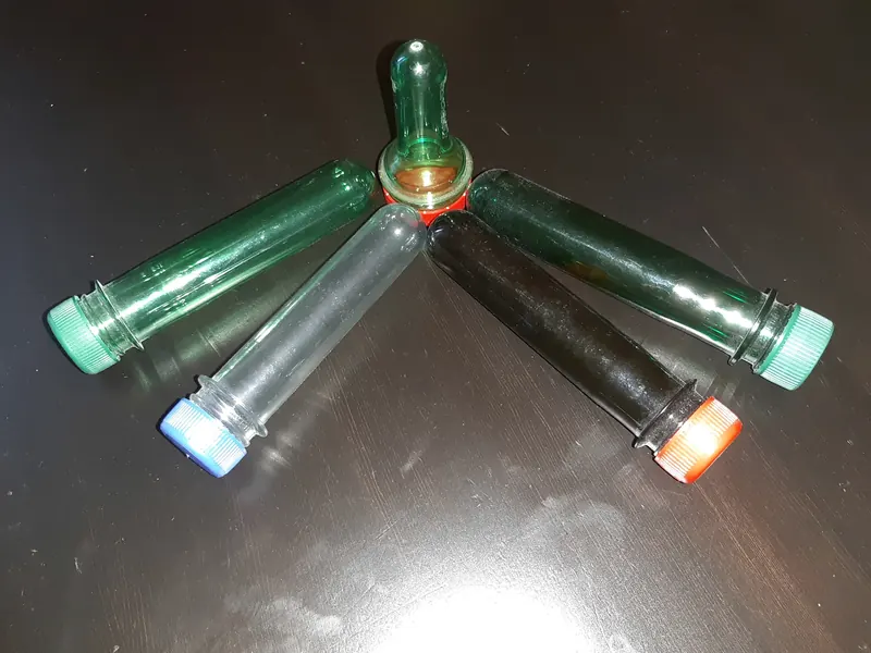 Coloured PET preforms arranged on a dark reflective surface